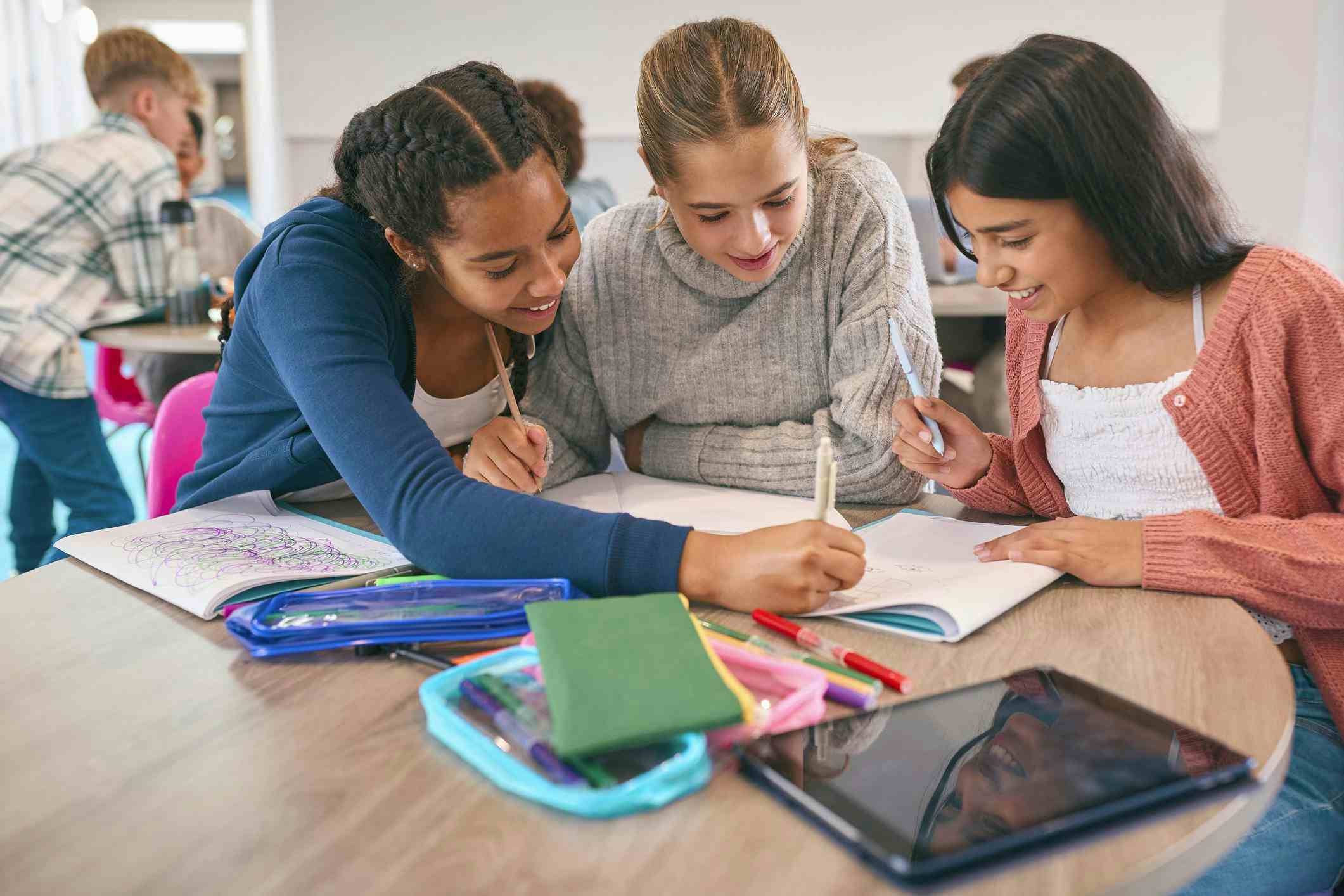 Three female high school students studying together around a table.