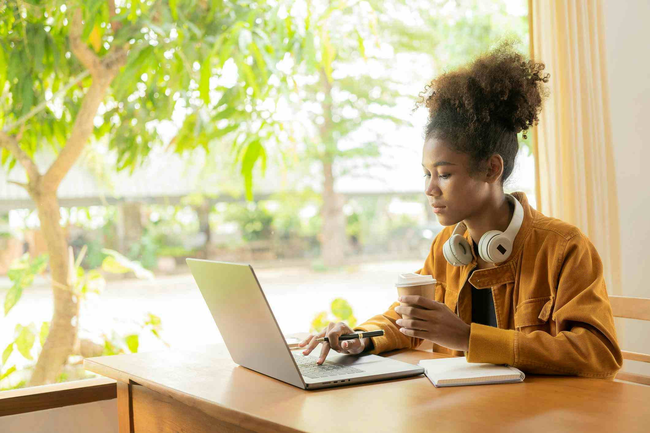 High School student sitting at a desk by the window working on her laptop