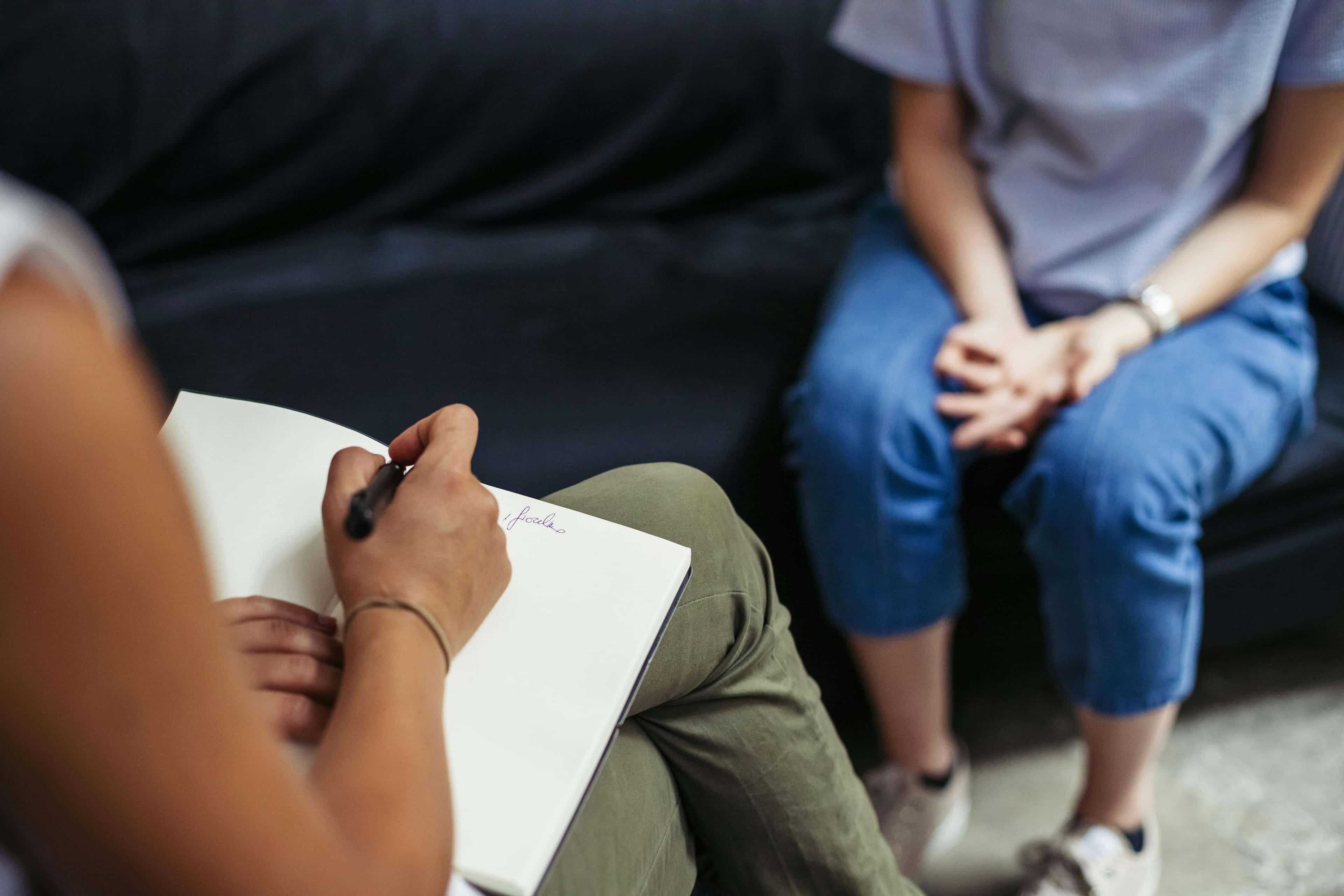 Women taking notes while listening to another women sitting on a couch