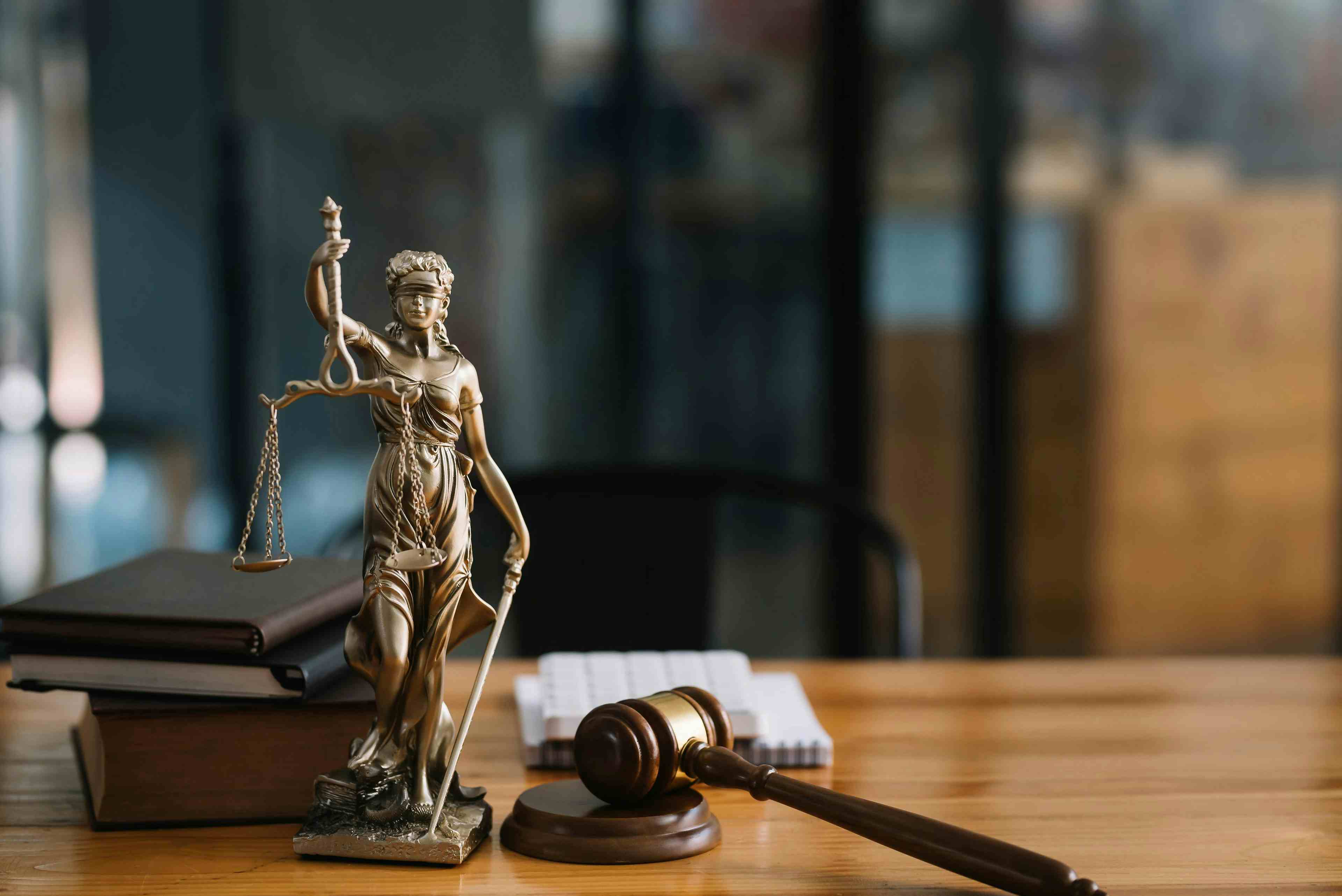 A statue of lady justice next to a gavel