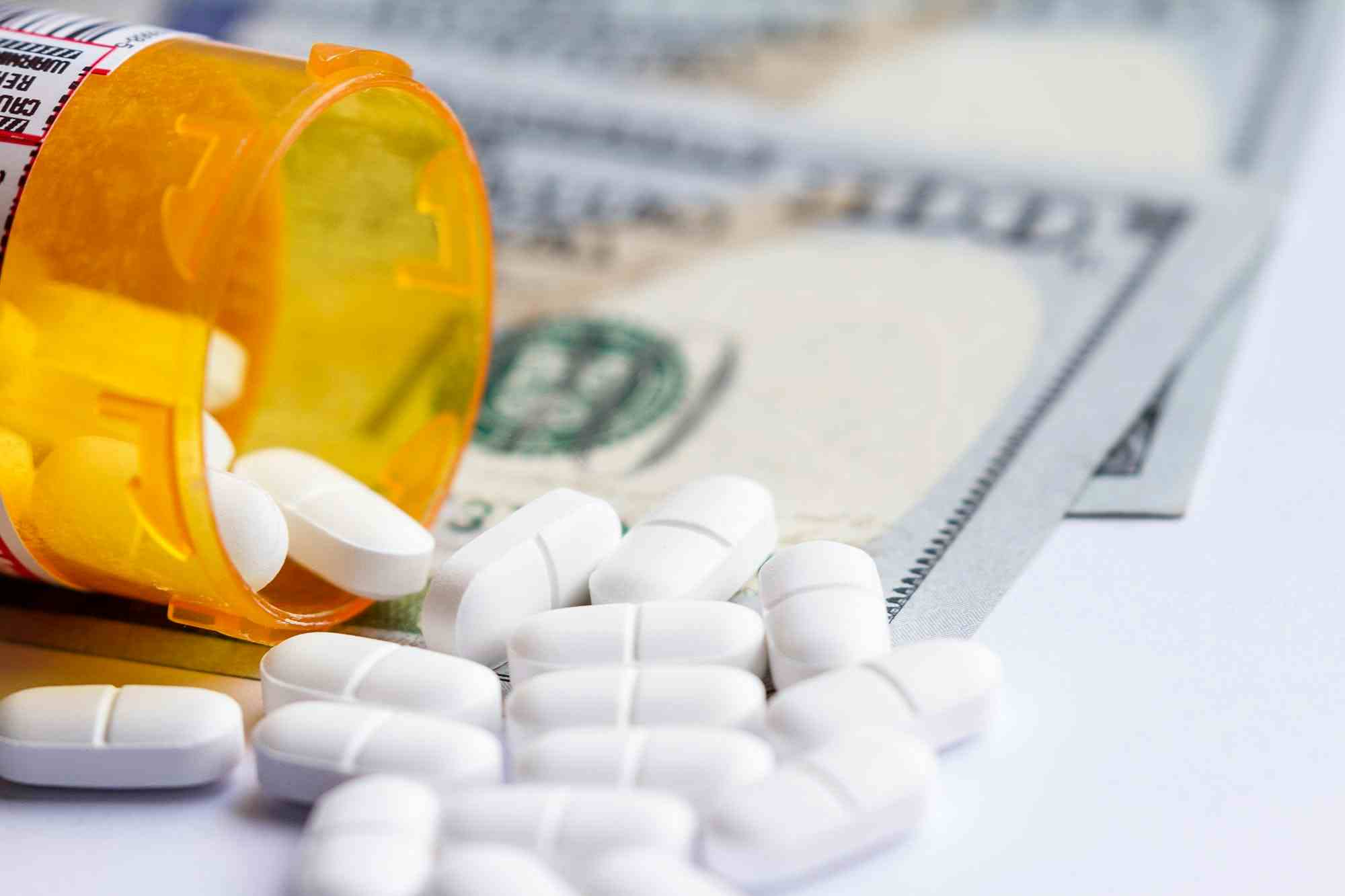 Prescription bottle, white pills, and United States currency