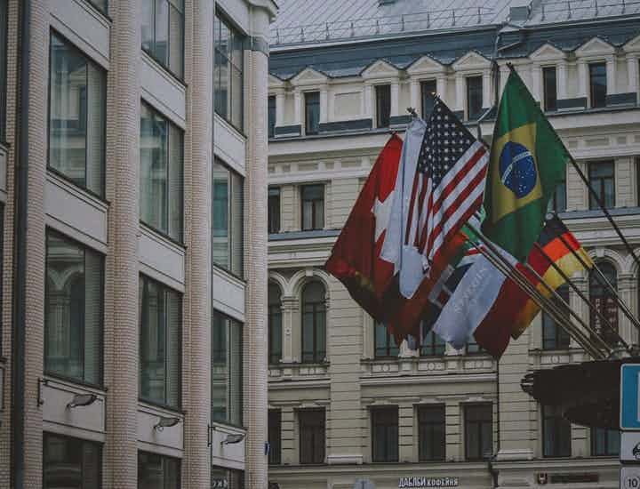 Many country's flag hanging outside large buildings